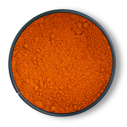 Runde schwarze Schale mit orange-rotem, gemahlenem Bio Roter Jalapeño Chili von oben gesehen.
