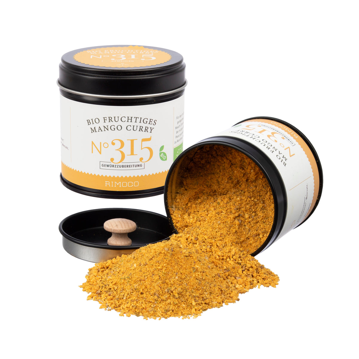 Eine offene Dose mit gelbem Currypulver, daneben ein Holzdeckel; zweite Dose teilweise sichtbar.