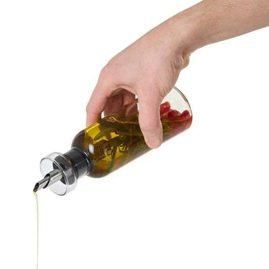 Aus dem AromaPour Öl- und Essigspender fließt Öl; im Inneren befinden sich Kräuter und Pfefferkörner.