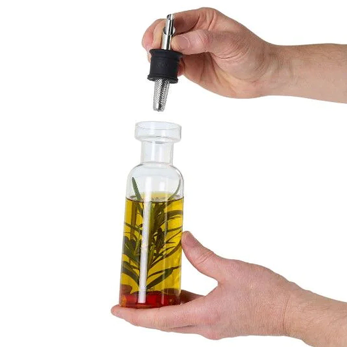 Eine Hand hält einen AromaPour Öl- und Essigspender und nimmt den Ausgießer mit Sieb ab.