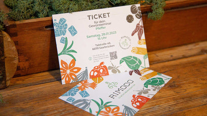 Zwei bunte Tickets Gewürzseminar Grundkurs mit Gewürzillustrationen auf Holztisch.