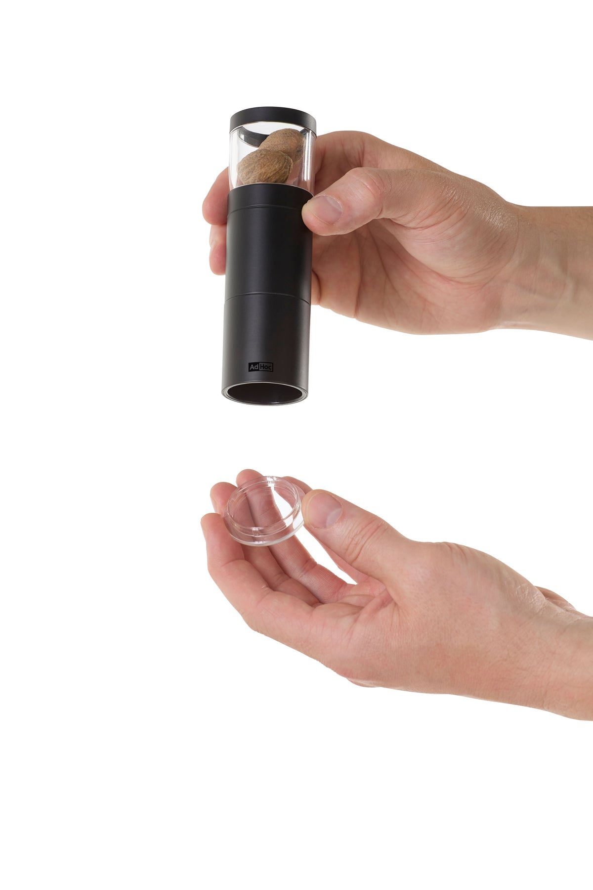 Gemahlene Gewürze werden aus einer Muskatreibe Muskatino schwarz in einen kleinen Behälter geschüttet.