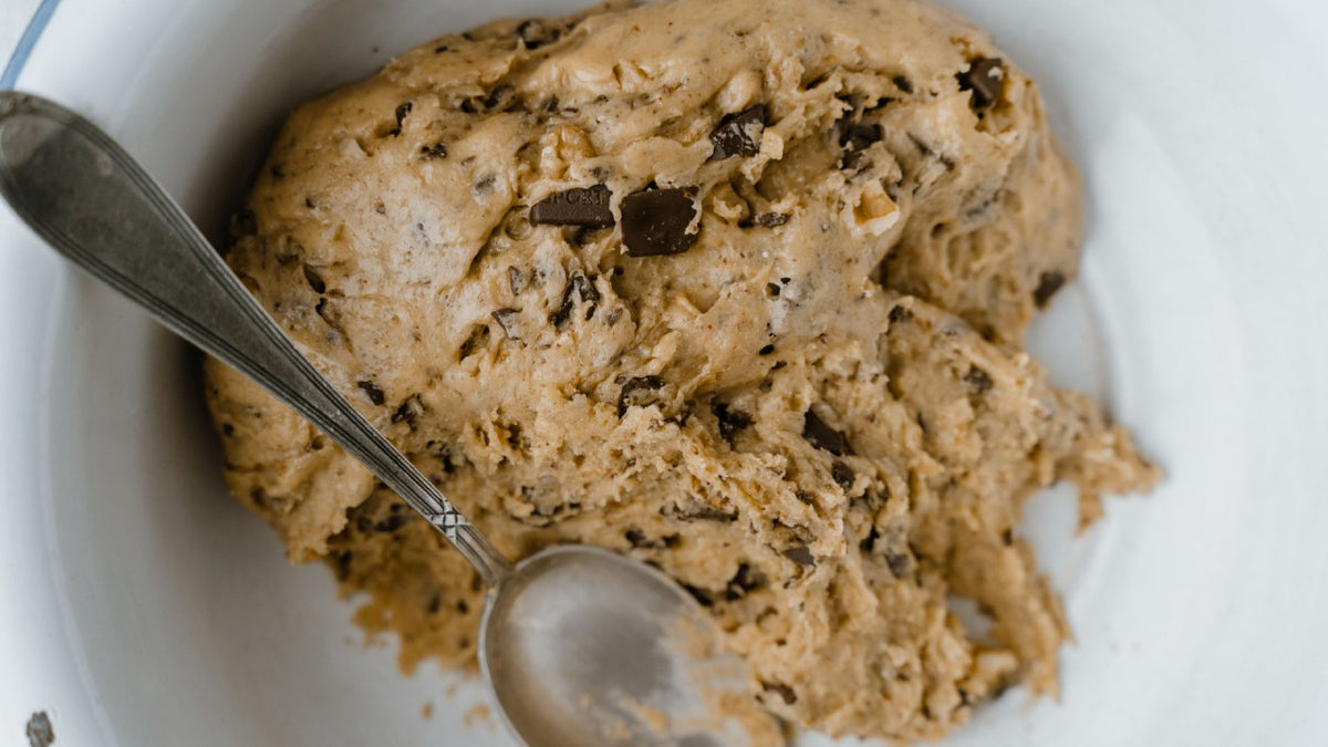 Schokostückchen-Cookieteig in einer rustikalen Schüssel mit einem Holzlöffel.