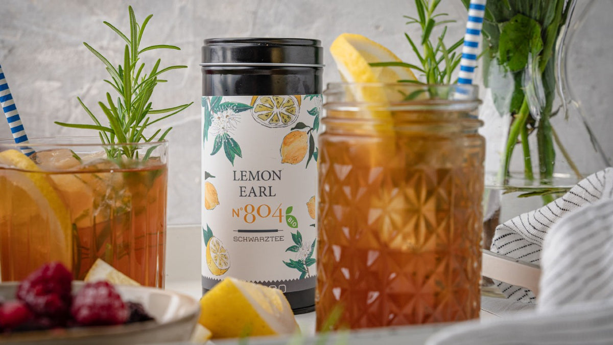 Lemon Earl Grey mit Zitronen-Rosmarin-Eistee neben einem Teller mit frischen Beeren.