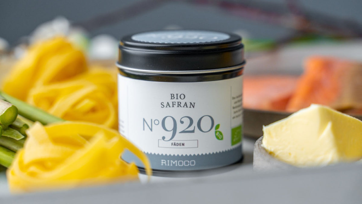 Bio Safran Nr. 920 – ein Glas neben Pasta, Butter und frischem Gemüse auf einem Tisch.