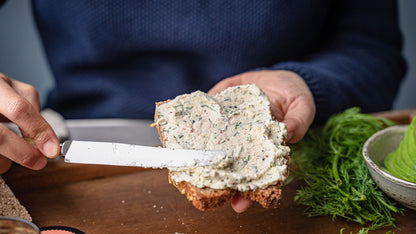 Frischkäse vom Dip Gewürze Set wird auf Brot gestrichen, dazu frische Kräuter und Avocado.