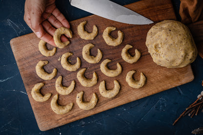 Eine Hand ordnet Halbmond-Plätzchen auf einem Blech.