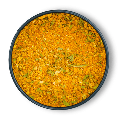 Ein rundes dunkles Gefäß mit Bio Aloo Gobi Gemüsecurry in Orange-Gelb und grünen Kräutern.