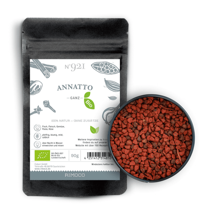 Schwarzer Bio Annatto Beutel neben einer Schale mit kleinen rotbraunen Annattosamen.