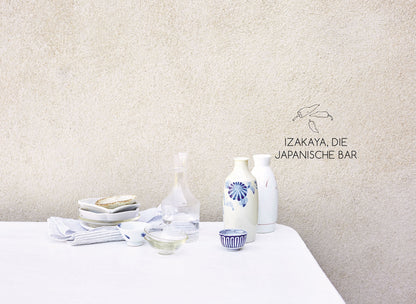 Japanisches Geschirr auf weißem Tisch, schlicht und minimalistisch arrangiert.