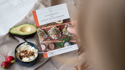 Avocado-Lachs-Toast-Rezeptkarte in einer Hand, daneben ein Gewürzset Mediterrane Gewürze.