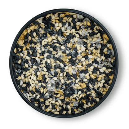 Schwarze Schale mit Bio Bagel Gewürz, schwarze und weiße Sesamsamen, grobes Salz, Draufsicht.