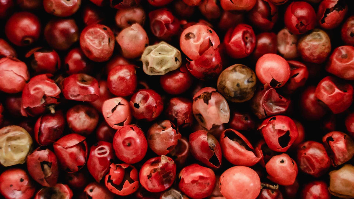 Nahaufnahme von roten und rosa Pfefferkörnern mit rissigen und faltigen Oberflächen.