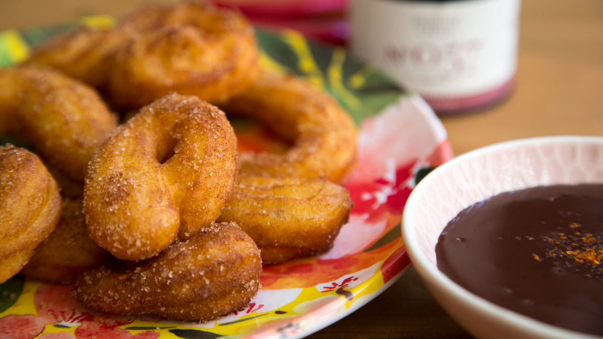 Gezuckerte Churros auf einem Teller mit Blumenmuster, dazu Bio Roter Jalapeño Chili Schokoladendip.