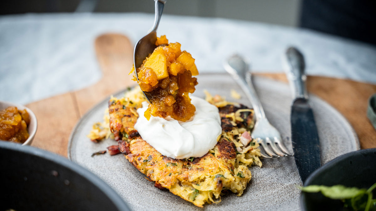 Saarlandrolle mit Sauerrahm und stückigem, orangem Chutney auf grauem Teller, Gabel daneben.