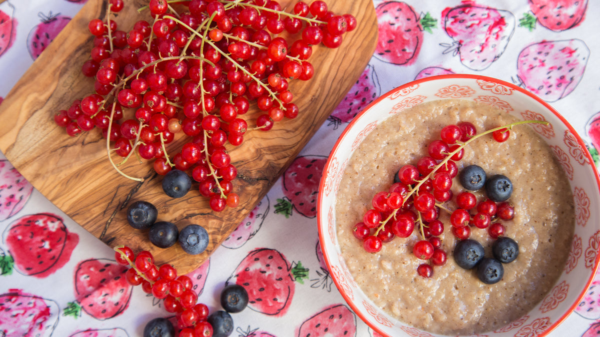 Schale mit Porridge, roten Johannisbeeren, Blaubeeren und etwas Bourbon Vanille & Honig obendrauf.