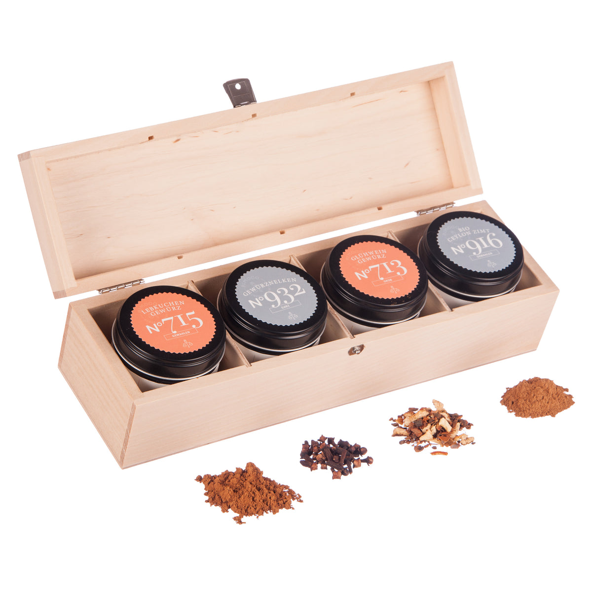 Holzbox mit vier Teedosen, Bio Ceylon Zimt, loser Tee und sichtbare Gewürze davor.