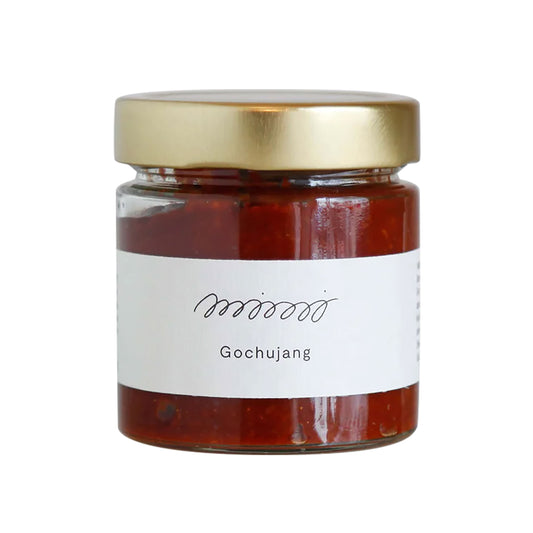 Bio Gochujang - koreanische Chilipaste im Glas mit goldenem Deckel und weißem Etikett auf weißem Hintergrund.