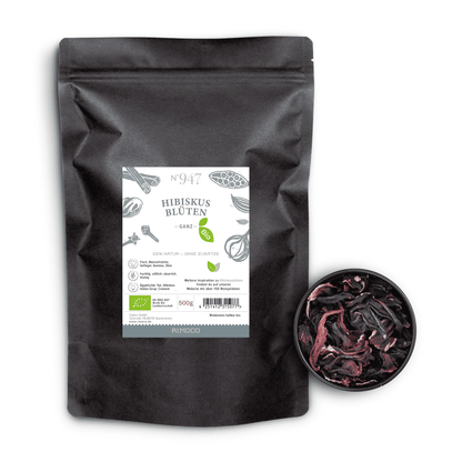 Schwarze Tüte mit Aufschrift Bio Hibiskusblüten ganz neben einer Schale getrockneter Hibiskusblüten.