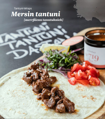 Tortilla-Wrap mit Rindfleisch, Tomaten, grünen Blättern und Zitronenscheibe auf einem Teller.