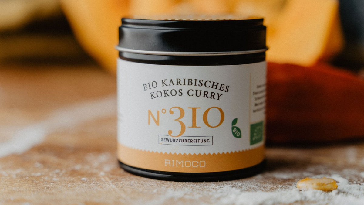 Das Bio-Karibische-Kokos-Curry Nr. 310 im Glas steht auf einer leicht bemehlten Oberfläche.