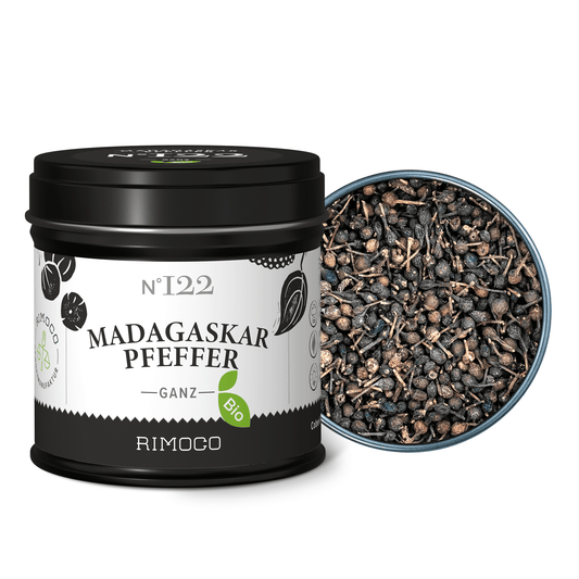 Eine Dose mit Aufschrift Bio Madagaskar Pfeffer neben geöffneten, ganzen Pfefferkörnern.