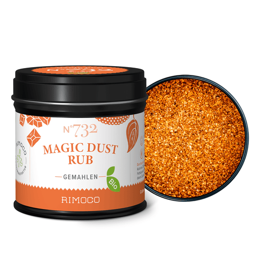 Offene Dosis Bio Magic Dust Rub mit orangefarbenem Gewürzpulver und Jaggery neben dem Deckel.