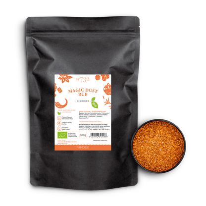 Schwarze Tüte Bio Magic Dust Rub neben einer Schale mit grobem, orangefarbenem Gewürz.