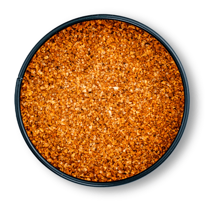 Rundes, schwarzes Gefäß mit grobem, orange-braunem Bio Magic Dust Rub von oben gesehen.