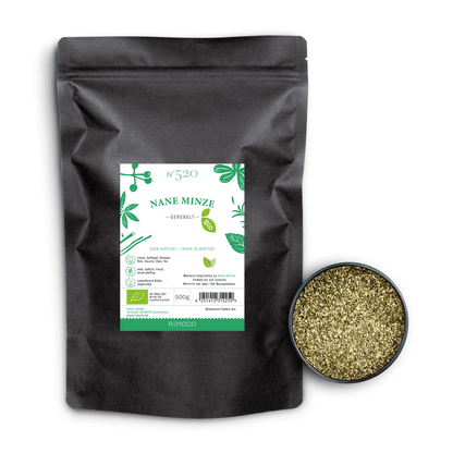 Schwarzer Beutel mit Aufschrift Bio Nane Minze neben einer Schale getrockneter Minzblätter auf Weiß.