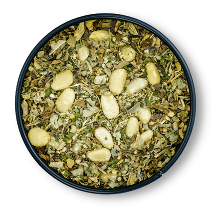 Bio Pesto Genovese in rundem Behälter mit gemischten getrockneten Kräutern und ganzen Pinienkernen.