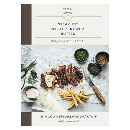 Geschnittenes Steak mit Pommes, Butter, Kräutern und groben Gewürzen auf Papier mit Besteck.
