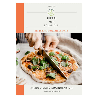 Eine Hand schneidet frische Pizza mit Basilikum, Pilzen, Wurst und Probierset Mediterrane Gewürze.