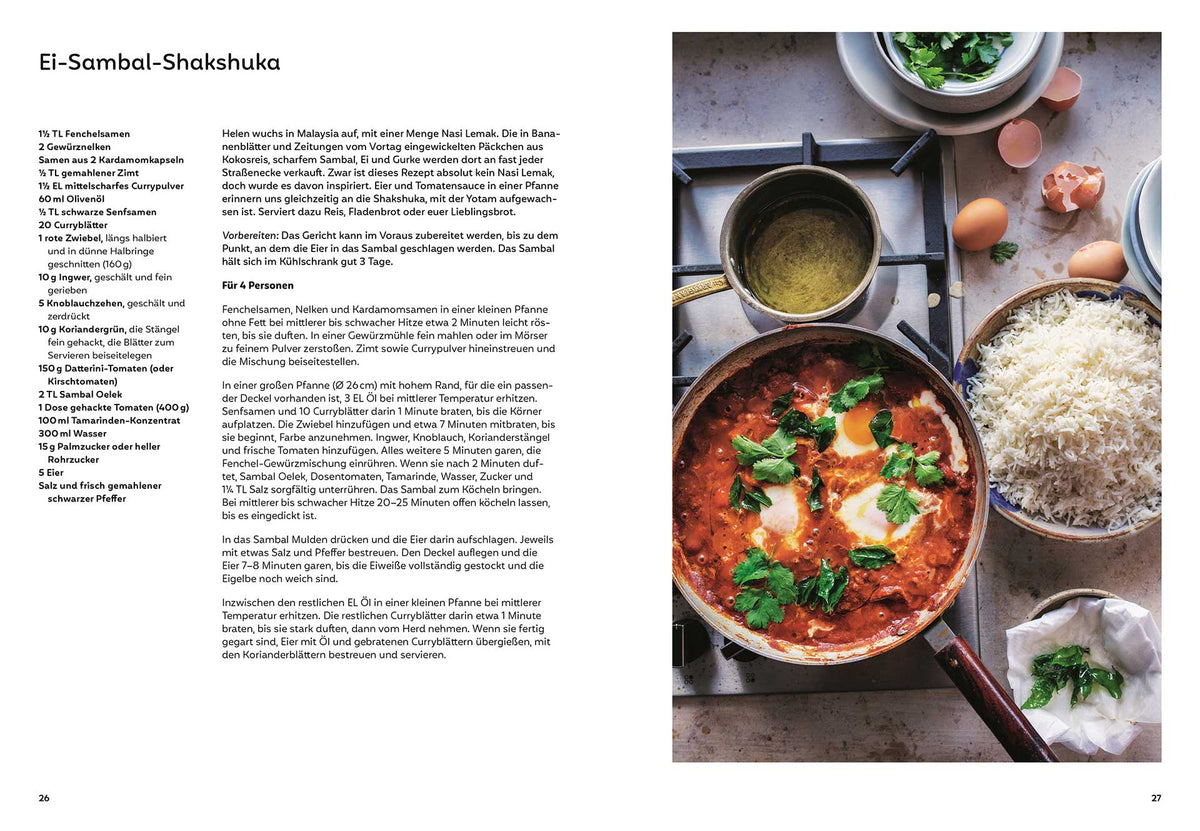 Eine Pfanne mit Shakshuka steht neben Reis und frischen Kräutern.