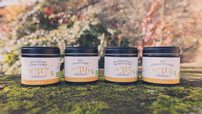 Vier Gläser Bio Curry Gewürz-Set N°2 mit gelben Etiketten stehen draußen auf Moos.