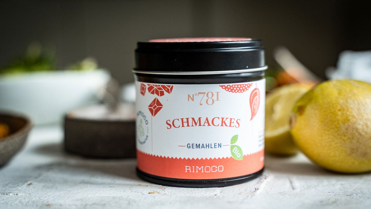 Gemahlene Schmackes von Rimoco auf weißem Untergrund neben frischen Zitronen.