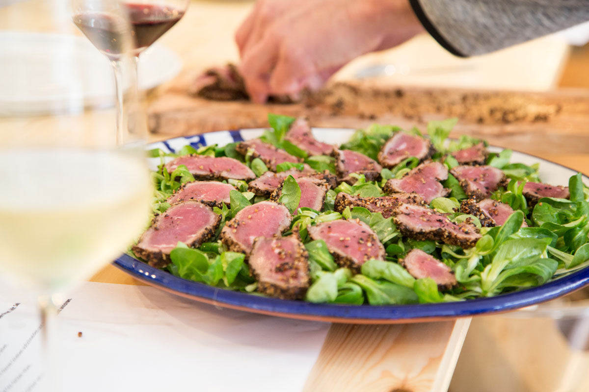 Gebratener Thunfisch auf Blattsalat, Glas Wein, Tischschild mit Gewürzseminar Pfeffer.