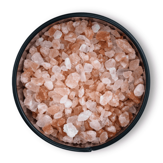Schwarze Schale mit groben rosa Kristallsalz-Kristallen, von oben gesehen.