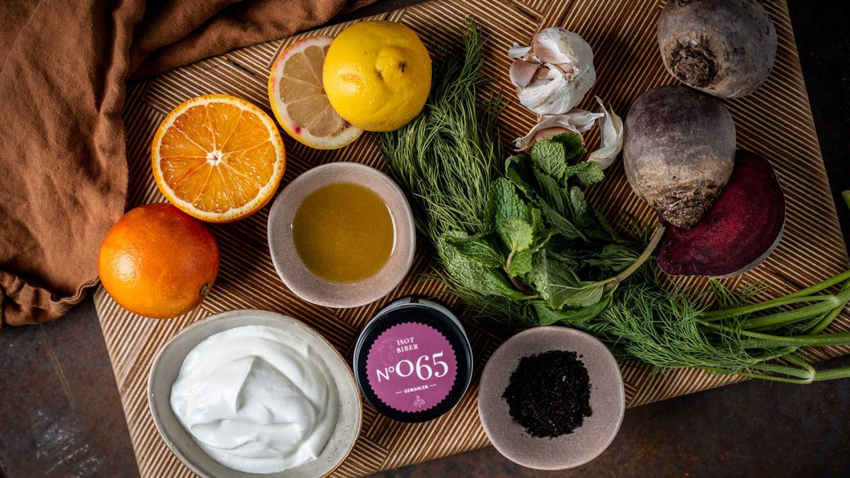 Ein Brett mit Orange, Zitrone, Knoblauch, Rote Bete, Joghurt, Öl, Salz, Kräutern und Gewürzpulver.
