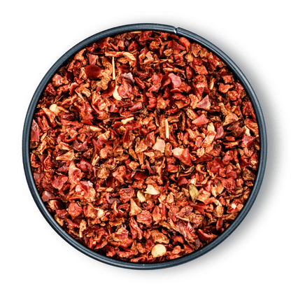 Schwarze Schale mit Bio Rote Paprikaflocken, von oben auf weißem Hintergrund fotografiert.