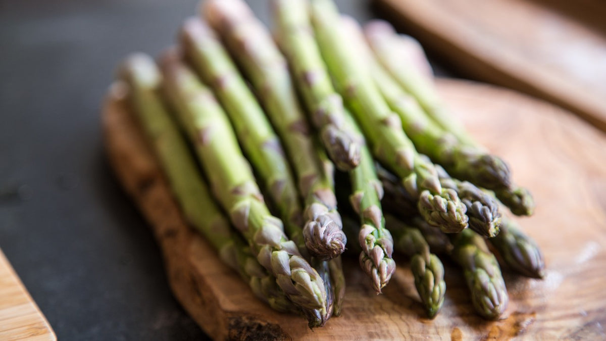 Ein Bund grüner Spargel auf einem Holzbrett.