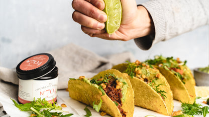 Tacos, über die eine Hand Limette auspresst, daneben ein Glas BBQ Probier-Set.