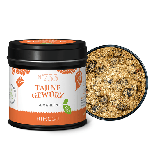 Runde Dose Bio Tajine Gewürz N°755 mit offenem Deckel, daneben die gemahlene Mischung mit Korinthen.