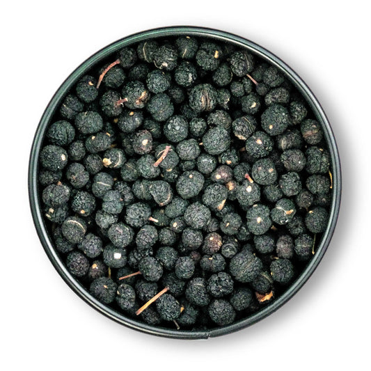 Runde Dose mit getrockneten schwarzen Maulbeeren und tasmanischem Bergpfeffer auf weißem Hintergrund.