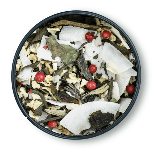 Eine Tasse weißer Tee mit Kokosraspeln und roten Pfefferkörnern.